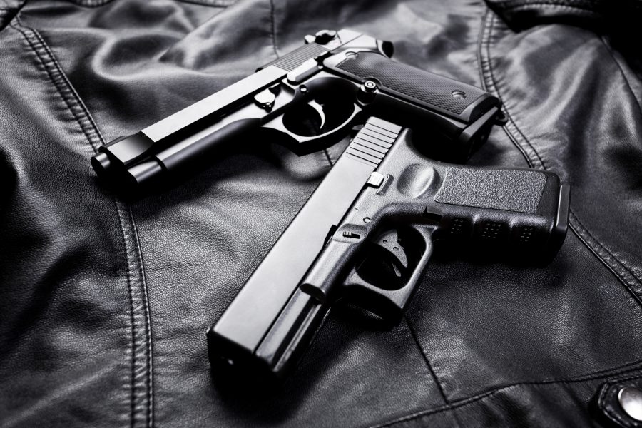 Two guns on a black leather background