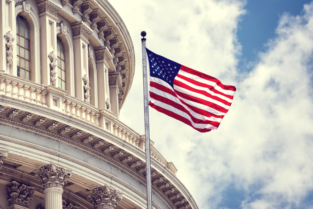 American flag flying with a cloudy blue sky background
