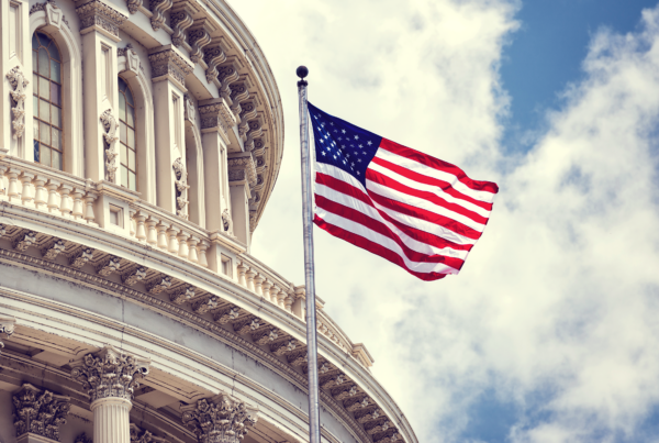 American flag flying with a cloudy blue sky background